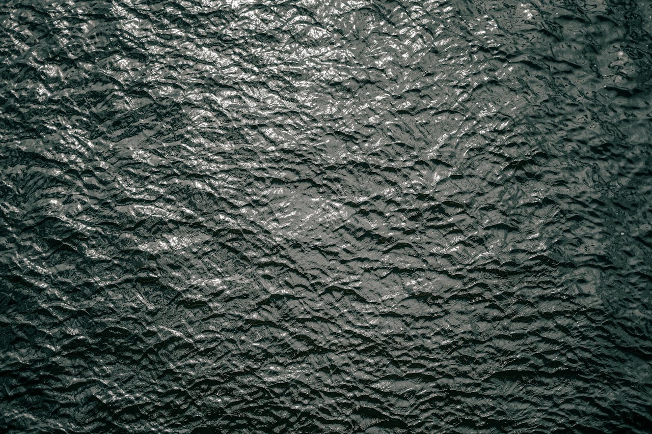 High-resolution image of rippling dark water surface texture, captured outdoors in Berlin, Germany.