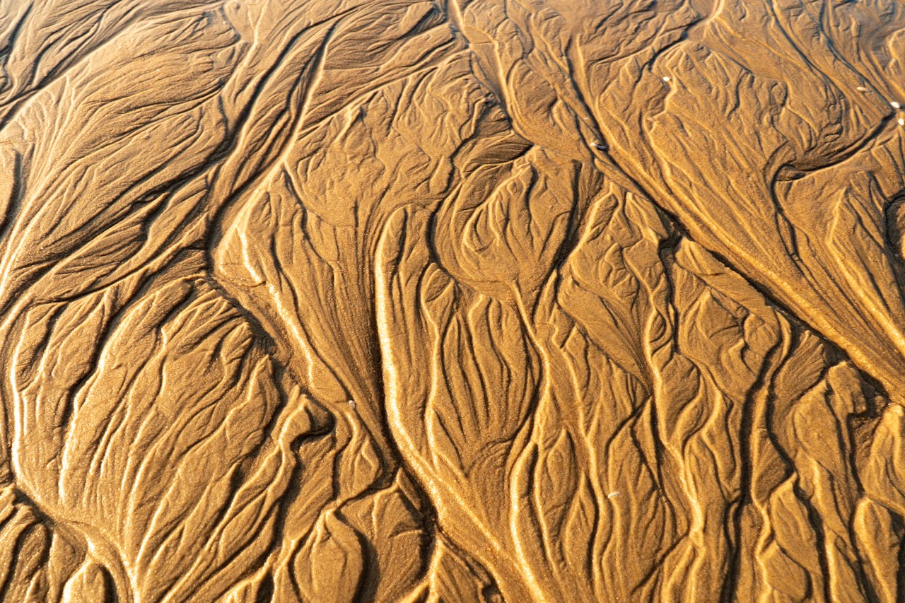 team-01 Stunning aerial view of intricate sand patterns on a Vietnamese beach, resembling natural abstract art.